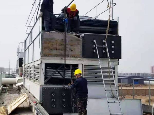 The construction workers are installing the closed circuit cooling tower.