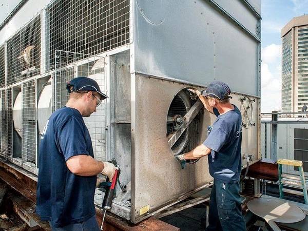 2 travailleurs vérifient les conditions de fonctionnement de la tour de refroidissement.